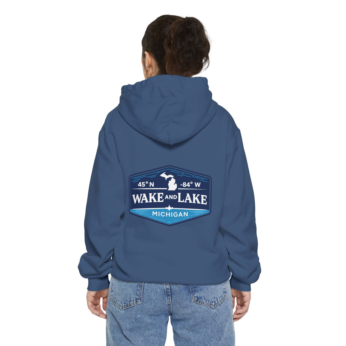 Model wearing the Wake and Lake Michigan Shield Hoodie – Premium in True Navy, back view showing the 45°N -84°W coordinate badge.